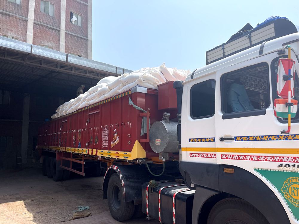 Flour sacks being stacked onto a truck outside a mill shed