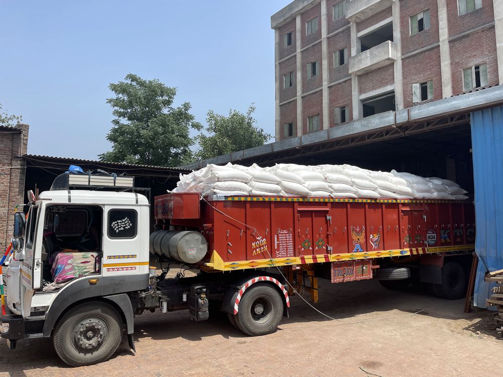 A truck loaded with flour sacks parked in front of a multi-storey flour mill