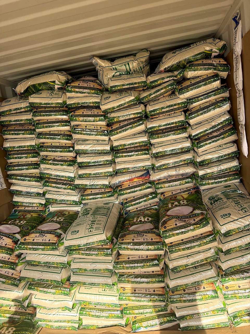 Printed 25 kg rice bags stacked floor to roof inside a shipping container