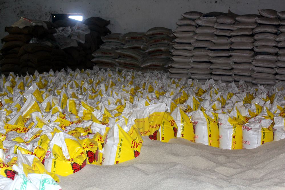 Milled rice heaped beside filled sacks inside a rice mill