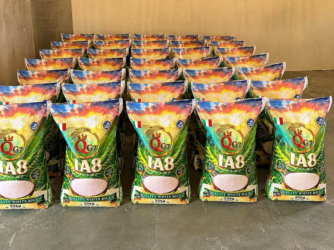 Neat rows of printed 25 kg quality white rice bags on a warehouse floor