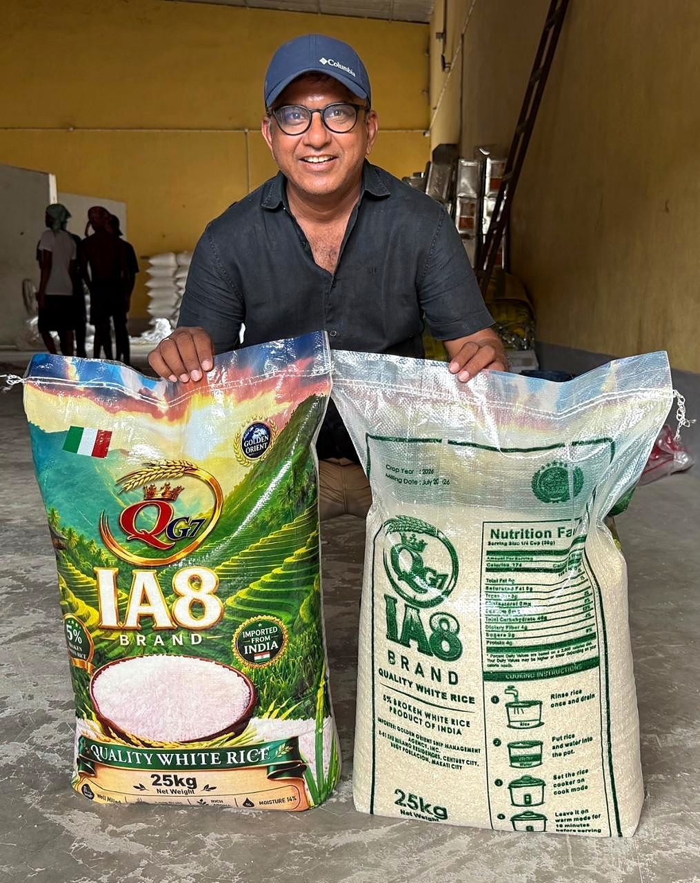 A man in a cap kneeling behind two printed 25 kg IA8 quality white rice bags, front and back
