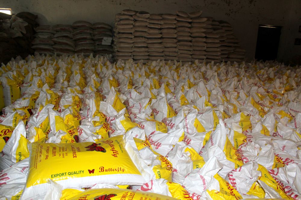 A mill floor covered with filled yellow and white rice sacks
